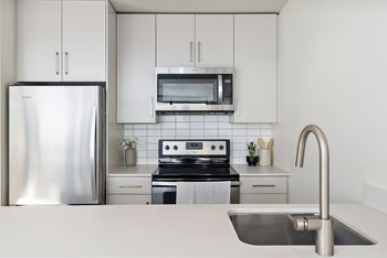 A modern kitchen with a stainless steel refrigerator, microwave, and oven.at Raymond Block, Edmonton Alberta T6E 3R7